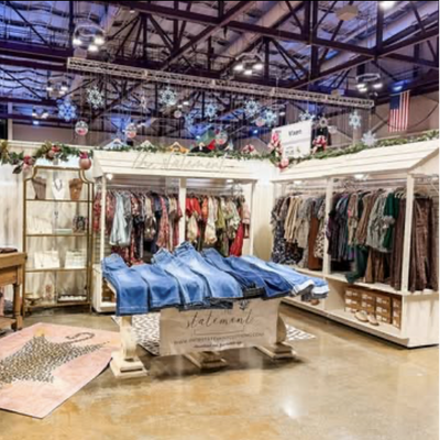 Retail store interior with clothing racks and display tables.